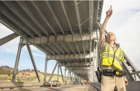  ?? Photos by Peter DaSilva / Special to The Chronicle ?? CHP Officer Bryan Williams points out where chunks of concrete broke loose and fell on the Richmond-San Rafael Bridge.