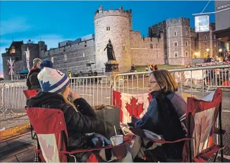  ?? EMILIO MORENATTI THE ASSOCIATED PRESS ?? A group of women from Canada sit outside Windsor Castle, England, Thursday. Preparatio­ns continue in Windsor ahead of the royal wedding of Britain’s Prince Harry and Meghan Markle on Saturday.