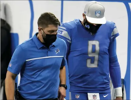  ?? PAUL SANCYA — THE ASSOCIATED PRESS ?? Detroit Lions quarterbac­k Matthew Stafford, left, walks off the field after injuring his hop during the second half of Sunday’s loss to the Green Bay Packers. The Lions coaching staff is holding out hope that Stafford will be play to play gainst the Tennessee Titans Sunday.