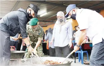  ?? — Bernama photo ?? Tunku Azizah watches as Al-Sultan Abdullah (second left), Tengku Ahmad Ismail and Pahang Menteri Besar Datuk Seri Wan Rosdy Wan Ismail (right) prepare food for flood evacuees at PPS Sri Damai.