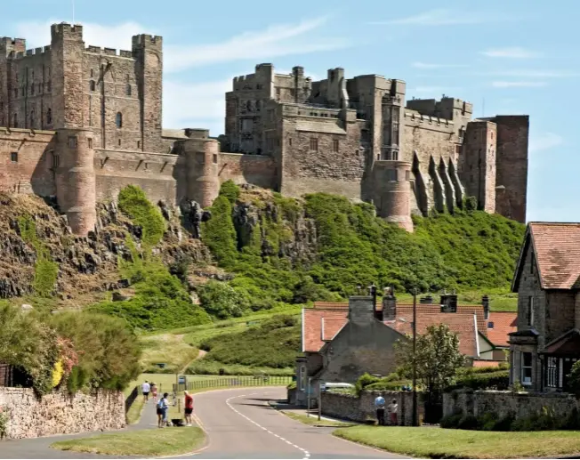  ??  ?? › Nestled at the foot of the castle, the pretty village of Bamburgh is dwarfed by its imposing bulwarks.
