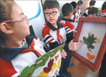  ?? HAO QUNYING / FOR CHINA DAILY ?? Students at a primary school in Handan, Hebei province, exchange views on their paintings made of leaves on Monday ahead of World Thrift Day, which falls on Oct 31.