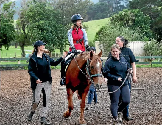  ?? CAMERON BURNELL/ FAIRFAX NZ ?? Laura Stuart, who has been in a wheelchair since a biking accident in February 2016, with New Zealand Riding for the Disabled staff.