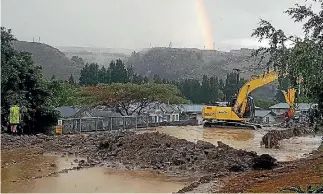  ?? PHOTO: NARDIA WEEDS ?? A digger sits in floodwater as it clears debris left on Roxburgh’s streets after flash flooding hit the area on Sunday afternoon.