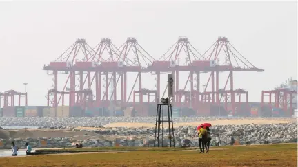  ??  ?? A couple walk on the Galle Face green as the China Port City project is seen behind in Colombo, Sri Lanka. (AP)