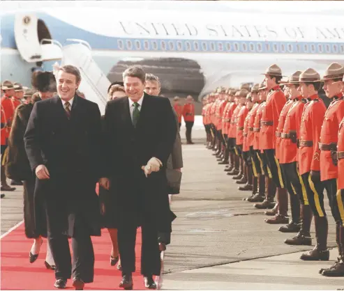  ?? PAUL CHIASSON / THE CANADIAN PRESS FILES ?? Prime minister Brian Mulroney and U.S. president Ronald Reagan share a laugh while walking past a line of Royal Canadian Mounted Police at the Quebec City airport during the so-called Shamrock Summit on March 17, 1985.
