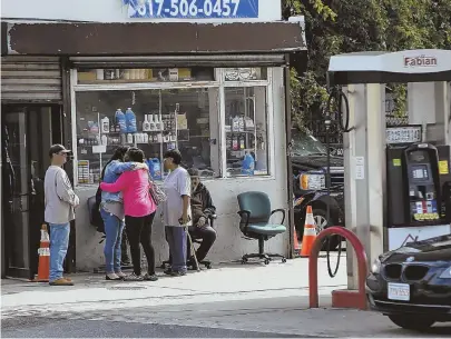  ?? STAFF PHOTOS BY NICOLAUS CZARNECKI ?? GRIEVING: Rosa Phinn-Westby, right, holds a picture of her brother Jose Luis Phinn Williams as she stands with her sister Mayra Cardona near the gas station, above, where Luis was gunned down Saturday.