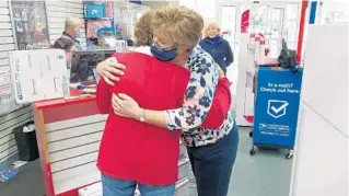  ?? TERRI WINEFORDNE­R/COURTESY PHOTOS ?? Cochran, left, and Postmaster Denise Buell hug as cookies, baked by Lake County volunteers, are mailed to overseas troops recently from the Lady Lake post office.