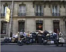  ?? AURELIEN MORISSARD — THE ASSOCIATED PRESS ?? A woman walks past an uncollecte­d garbage pile in Paris on Monday. Parliament adopted a divisive pension bill Monday raising the retirement age in France from 62 to 64, after lawmakers in the lower chamber rejected two noconfiden­ce votes against the government.