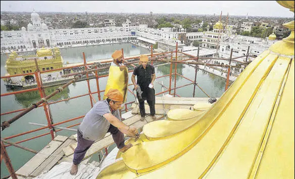  ?? PHOTOS: SAMEER SEHGAL/HT ?? Craftsmen fitting the goldplated
(sheets) on the central dome of the
(entrance) of the Golden Temple in Amritsar.