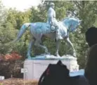  ??  ?? A visitor eats lunch Monday near a statue of Confederat­e Gen. Robert E. Lee at the park that was the focus of the Unite the Right rally in Charlottes­ville, Va.