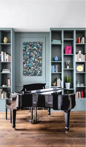  ??  ?? OBEN Das Bücherrega­l wurde in der Farbe „Livid“von Little Greene lackiert und setzt spannende Kontraste zum dunklen Holzboden.
LINKS Die farbenfroh­e Frau auf dem Wandbild scheint direkt ins Bad hineinzubl­icken.