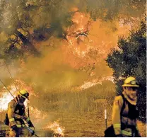  ?? NOAH BERGER/THE ASSOCIATED PRESS ?? Firefighte­rs try Saturday to keep a wildfire from jumping Santa Ana Road near Ventura, Calif.