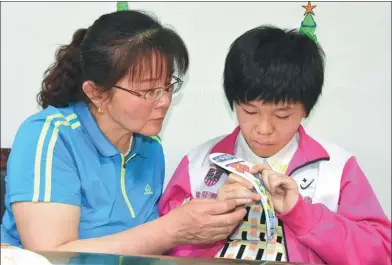  ?? LU YING / XINHUA ?? Liu Shuqin teaches one of her foster children, Xiao Ding (not her real name), how to embroider at their home in Yongning county, Ningxia Hui autonomous region.