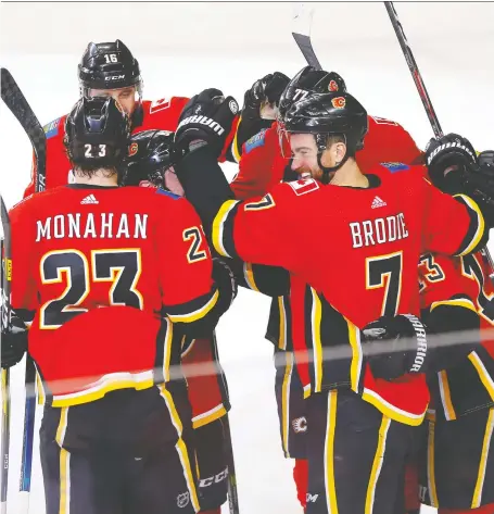  ?? DARREN MAKOWICHUK ?? Flames defenceman TJ Brodie is mobbed by teammates after scoring the game-winner in overtime as Calgary nipped the Columbus Blue Jackets 3-2 on Wednesday night at the Scotiabank Saddledome. The win opened a five-game homestand on a winning note.