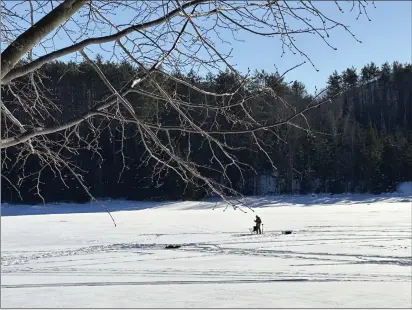  ?? PHOTOS BY LISA RATHKE — THE ASSOCIATED PRESS ?? An ice fisherman stands on the frozen Molly's Falls Pond in Marshfield, Vt., on Sunday.