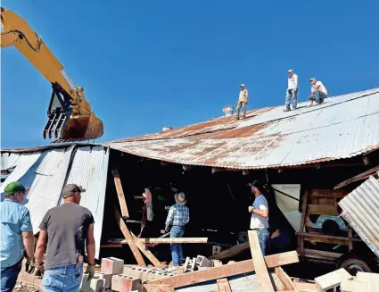  ?? JOHN STOTTS ?? Longtime neighbors and friends who came unbidden to the site of a damaged barn on land owned by the Nowakowski­s near Dale discuss how to safely remove a combine, implements and hay from the collapsed structure.