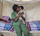  ??  ?? An Ebola survivor now immune to the virus held a child whose mother was being tested for the disease in Beni, Congo.