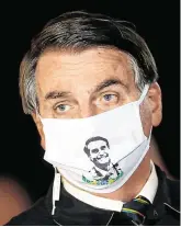  ?? PHOTO: ADRIANO MACHADO/ REUTERS ?? Leader: Jair Bolsonaro wears a mask bearing an image of himself as he speaks to reporters in Brasilia at the weekend.