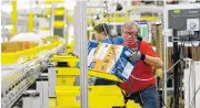  ?? ASSOCIATED PRESS FILE PHOTO ?? Mark Oldenburg processes outgoing orders at Amazon’s fulfillmen­t center in DuPont, Wash.