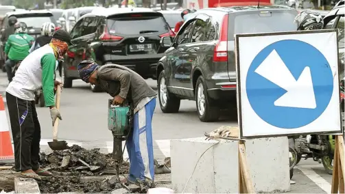  ?? ROBERTUS RISKY/JAWA POS ?? JALAN JADI SEMPIT: Dua pekerja membongkar aspal di Jalan Bratang Binangun untuk pemasangan box culvert kemarin (23/12).