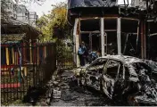  ?? AP ?? Residents check the damage at a shop destroyed during a Russian attack in Kherson, Ukraine, Friday. A barrage of missiles struck the recently liberated city.