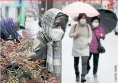  ??  ?? Pedestrian­s walk past a masked statue in the virus-hit city of Daegu, South Korea.