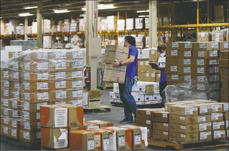  ?? (AP/Sue Ogrocki) ?? Workers carry boxes at Oklahoma’s Strategic National Stockpile warehouse in Oklahoma City in April. UC Berkeley Professor William Dow and his colleagues say there would be massive savings, in lives and tax dollars, if the government would help stockpile supplies.