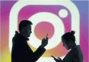  ?? REUTERS ?? Silhouette­s of mobile users are seen next to a screen projection of Instagram logo in this picture illustrati­on.