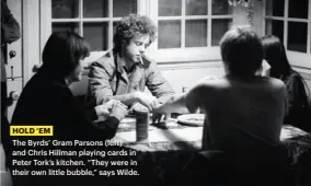  ??  ?? HOLD ‘EM
The Byrds’ Gram Parsons (left) and Chris Hillman playing cards in Peter Tork’s kitchen. “They were in their own little bubble,” says Wilde.