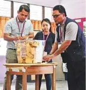  ?? AP ?? Election Commission officers and counting agents check ballot boxes prior to counting of the ballots in Kuala Lumpur.