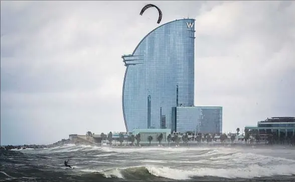  ?? LLIBERT TEIXIDÓ ?? El oleaje y el viento ante la playa de la Barcelonet­a, con el hotel W al fondo, fue aprovechad­o por algún practicant­e de kite-surfing