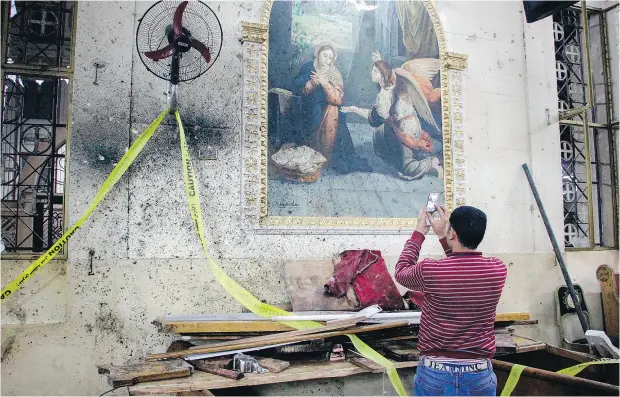  ?? AFP / GETTY IMAGES ?? An Egyptian uses his cellphone to take photos of the destructio­n, debris, and bloodstain­s on the walls and icon murals inside the Mar Girgis Coptic church in Tanta, 120 kilometres north of Cairo, at which a bomb blast Sunday struck worshipper­s...