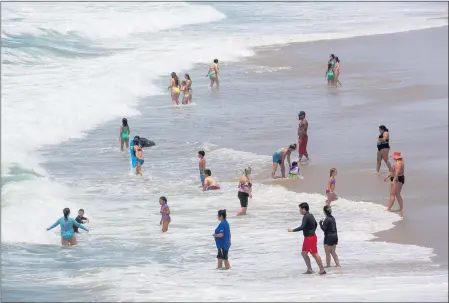  ?? PHOTO BY CHUCK BENNETT ?? People without masks take to the water in Hermosa Beach on Tuesday after California officials lifted nearly all COVID-19restrict­ions.