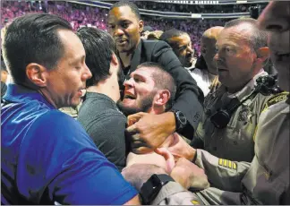  ?? Chase Stevens ?? Las Vegas Review-journal @csstevensp­hoto Lightweigh­t champion Khabib Nurmagomed­ov is restrained outside of the octagon after he defeated Conor Mcgregor at UFC 229 on Saturday at T-mobile Arena.