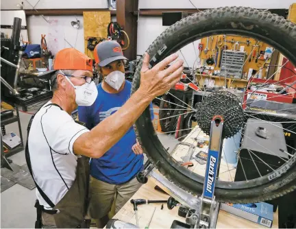  ?? PHOTOS BY MATT DAHLSEID/THE NEW MEXICAN ?? ABOVE: Jan Bear, left, and Charlie O’Leary inspect a mountain bike wheel Tuesday at O’Leary Built Bicycles. O’Leary says more customers are willing to wait for him to build a custom bike since they can’t find a manufactur­ed one for sale at a store. ‘I’ve had some customers who would’ve bought a bike off [a competitor’s] showroom floor if they could get it, but they can’t get it,’ O’Leary said.