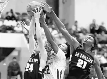  ?? STEPHEN M. DOWELL/ORLANDO SENTINEL ?? Dr. Phillips players Ledger Hatch (24) and Ernest Udeh Jr. (21) reach for a rebound against Jeremiah Bannister of Oak Ridge in Friday’s Class 7A semifinal at the R.P. Funding Center in Lakeland on Friday.