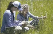  ??  ?? Kristen Podolak, left, an ecologist with the Nature Conservanc­y, looks up a flower for Lucy Blake, president of the Northern Sierra Partnershi­p, at Carpenter Ranch.