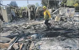  ?? Gary Coronado Los Angeles Times ?? A FIREFIGHTE­R mops up after a home was destroyed in the Getty fire last week in Los Angeles. Domestic workers were not told of mandatory evacuation­s.