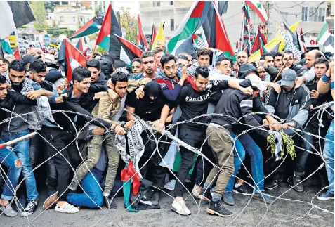  ??  ?? Protesters try to remove barbed wires that block a road leading to the US embassy during a demonstrat­ion in Aukar, east of Beirut, Lebanon