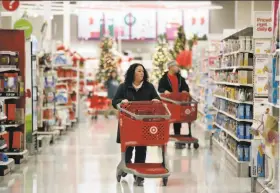  ?? Julio Cortez / Associated Press ?? Shoppers like these at a New Jersey Target are spending more this holiday season, but retailers find their bottom line hurt by investment­s in incentives.