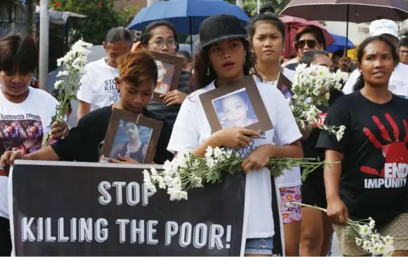  ?? BULLIT MARQUEZ/THE ASSOCIATED PRESS ?? Relatives of three Filipino youths, who were killed in an alleged anti-illegal drug operation in 2016, march to lay flowers and light candles at their tombs in Caloocan, north of Manila, Philippine­s.