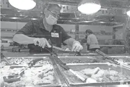  ?? JAVIER ARCE/LA VOZ ?? With face mask and gloves, a cook at Los Altos Ranch Market prepares a dish.