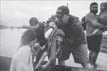  ?? Washington Post photos by Jabin Botsford ?? ABOVE: Glenda Montelonge­o, Richard Martinez and his two sons are helped out of a boat after being rescued Tuesday near Tidwell Road and Toll Road 8 in Houston.