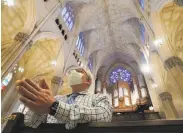  ?? Bryan R. Smith / AFP / Getty Images ?? A man prays inside St. Patrick’s Cathedral in New York City after it reopened at 25% capacity.