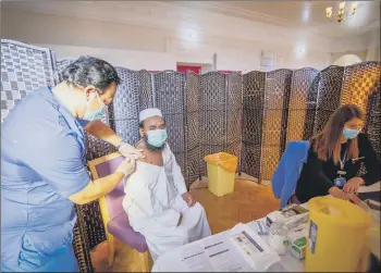  ??  ?? JAB DONE Dr Ebadur Chowdhury giving the vaccine to one of the imaans, MD Golem Rahman with Miranda Smith registrati­ng his details