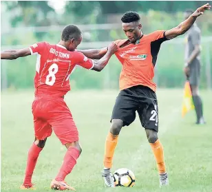  ?? RICARDO MAKYN ?? Boys’ Towns’ Garfield Gillespie (left) grabs the shirt of Tivoli Gardens’ Andre Moulton in their Red Stripe Premier League encounter at the Barbican field yesterday. Tivoli Gardens won the game 4-2. Teams