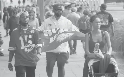  ?? CHARLIE RIEDEL/AP ?? People walk near Super Bowl activities Friday in Tampa, Florida. As the pandemic rages on with virus variants emerging, health officials are concerned that Super Bowl parties and get-togethers could become supersprea­der events.