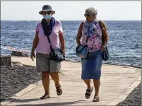  ?? JOAN MATEU / ASSOCIATED PRESS ?? SPAIN: A woman wears a face mask Friday at Enramada beach in La Caleta, Tenerife, the largest of Spain’s Canary Islands. Some guests have started to leave a locked down hotel nearby after undergoing screening for coronaviru­s.