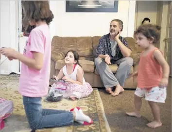  ?? Photograph­s by Brian van der Brug Los Angeles Times ?? SYRIAN REFUGEE Taiseer Al Souki relaxes at home with his family in Fresno. He is grateful for his exhausting job at a Foster Farms poultry plant, feeding large plastic boxes into a machine that cleans them.